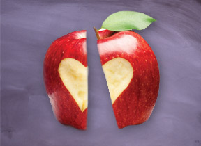 An apple with a heart share carved into it, sliced in two