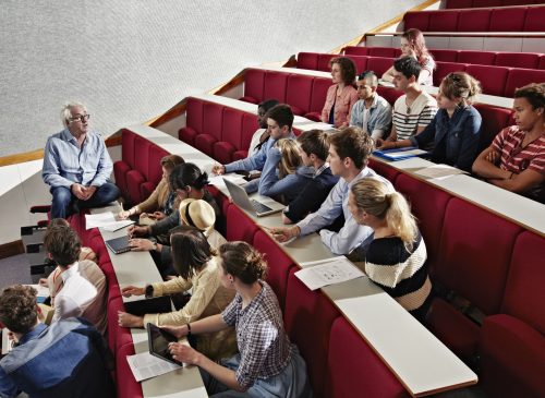 A professor speaks to students in a lecture hall.