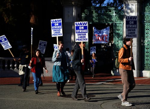 Faculty strike on a picket line outside a building
