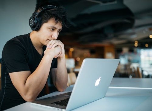 A person with headphones on watching a laptop.